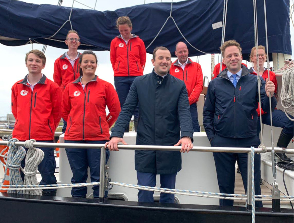 Seven Sea Rangers in uniform stand on a boat, posing for a photo. With them are Sea Ranger Service founder Wietse van der Werf, and the European Commissioner for Environment, Oceans and Fisheries, Virginijus Sinkevičius.