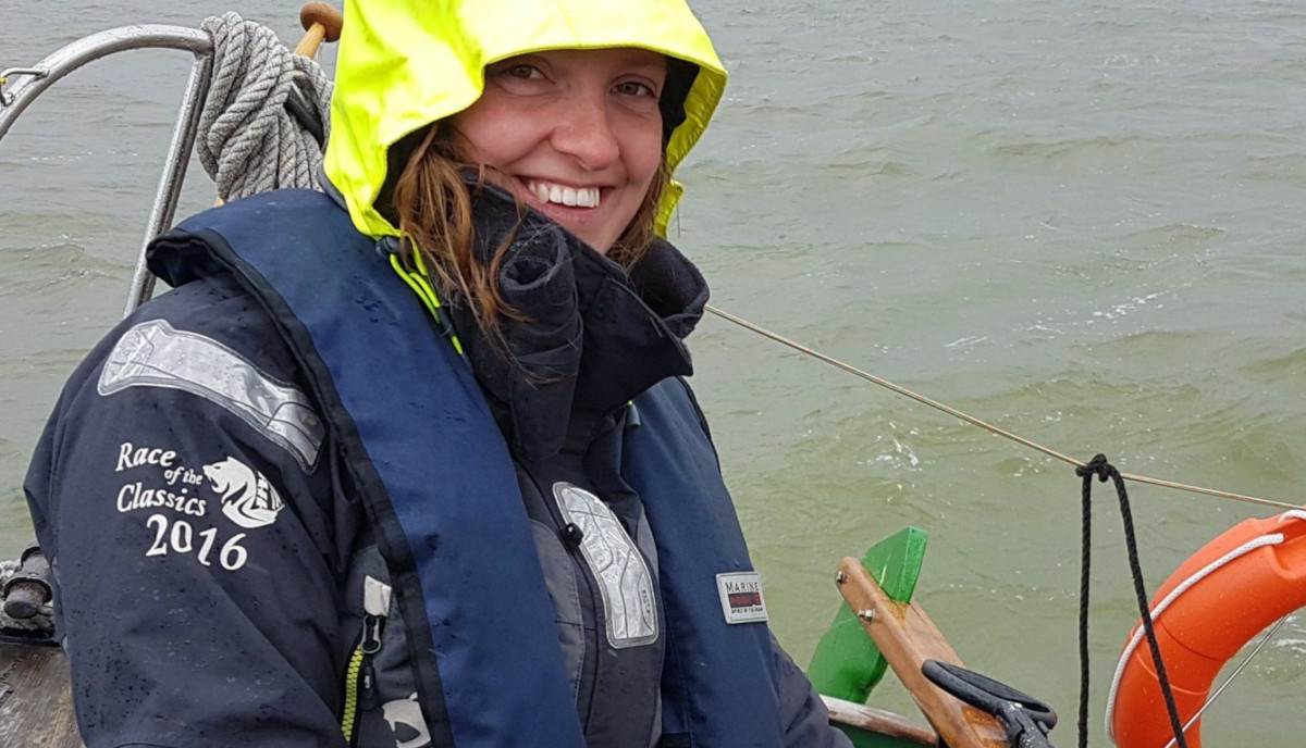 A close up of Sea Ranger Vera, on board a Sea Ranger vessel out at sea. Vera has a florescent yellow hood up and is smiling at the camera.