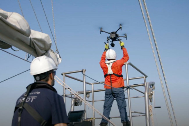 A Sea Ranger on a boat, out at sea, setting up a drone to carry out ocean conservation work.
