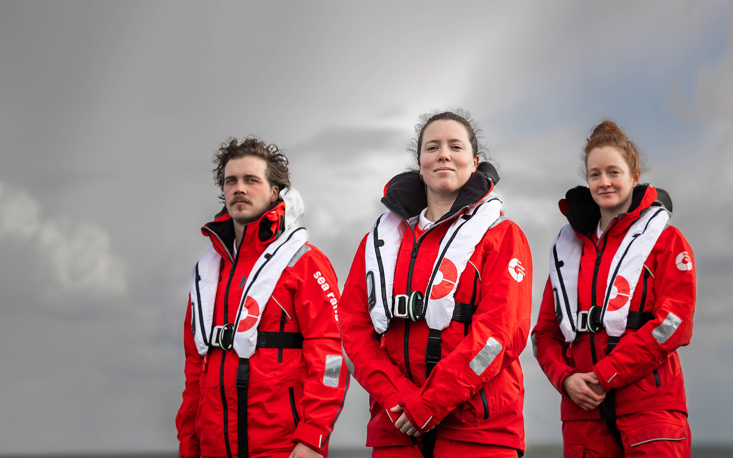 Three Sea Rangers in uniform posing for a photo against a cloudy background.
