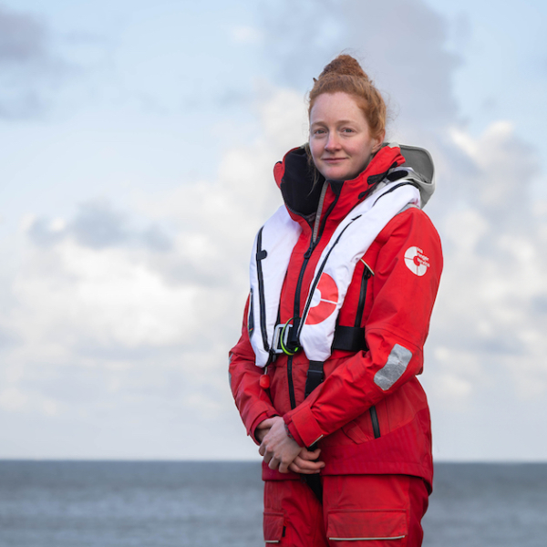 A female Sea Ranger in uniform posing in front of a sea scape.